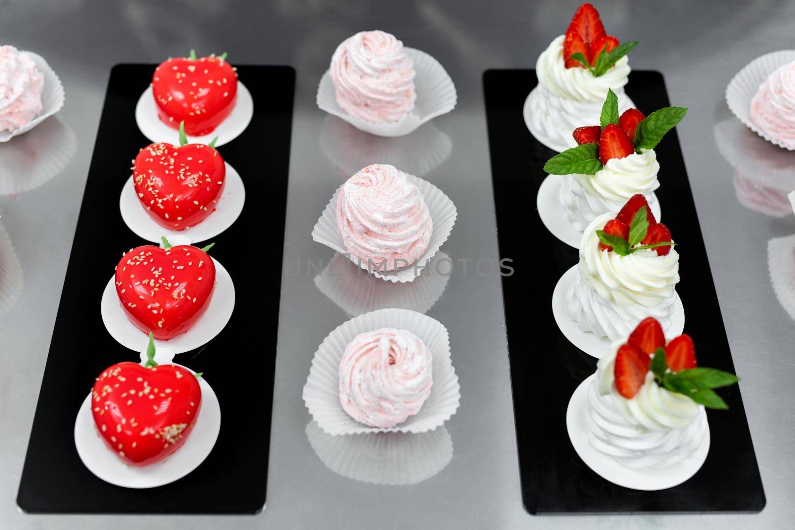 Pavlova meringue, marshmallows and mousse cake on the table in the pastry shop.