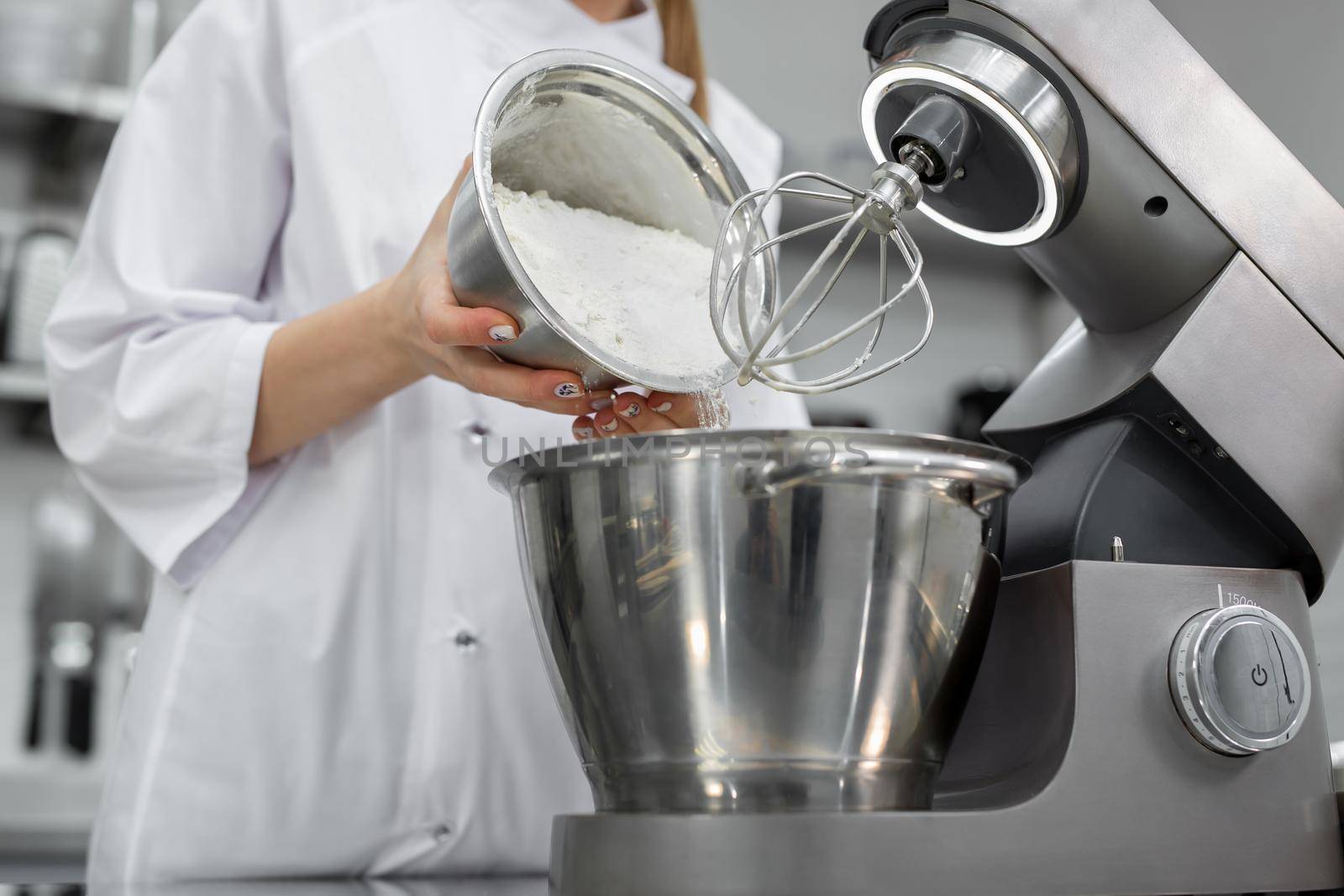 Pastry chef adds flour to the bowl of the mixer by StudioPeace