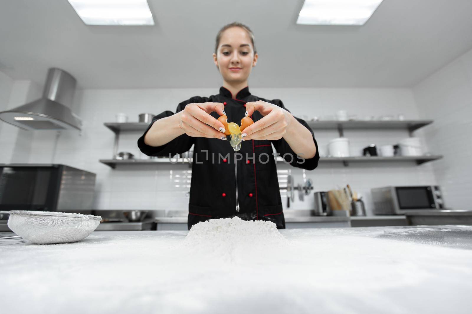 Pastry chef cracking an egg over white flour. by StudioPeace