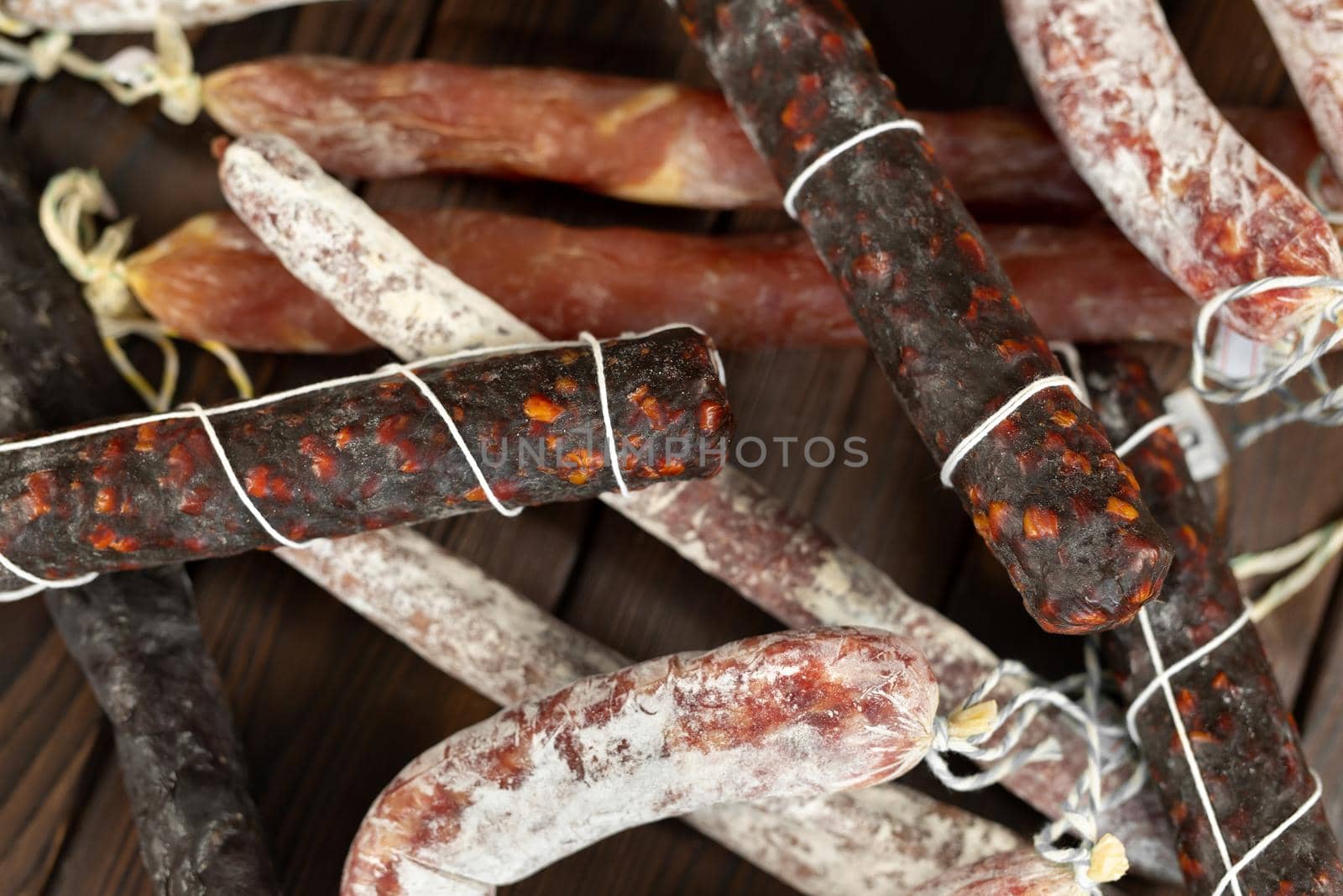 A variety of sausage products in close-up on a brown wooden background by StudioPeace