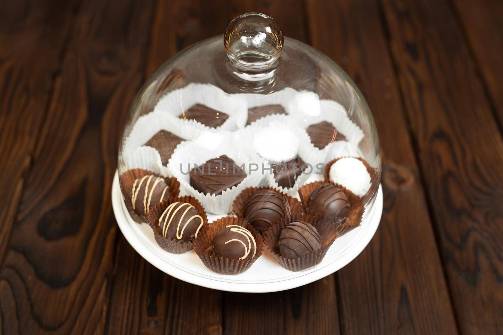 Handmade chocolates on a tray under a glass cover.