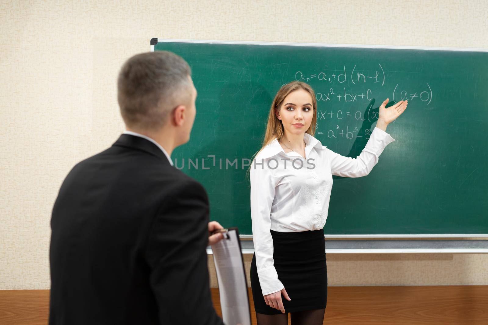 Young student girl takes an exam near the blackboard.