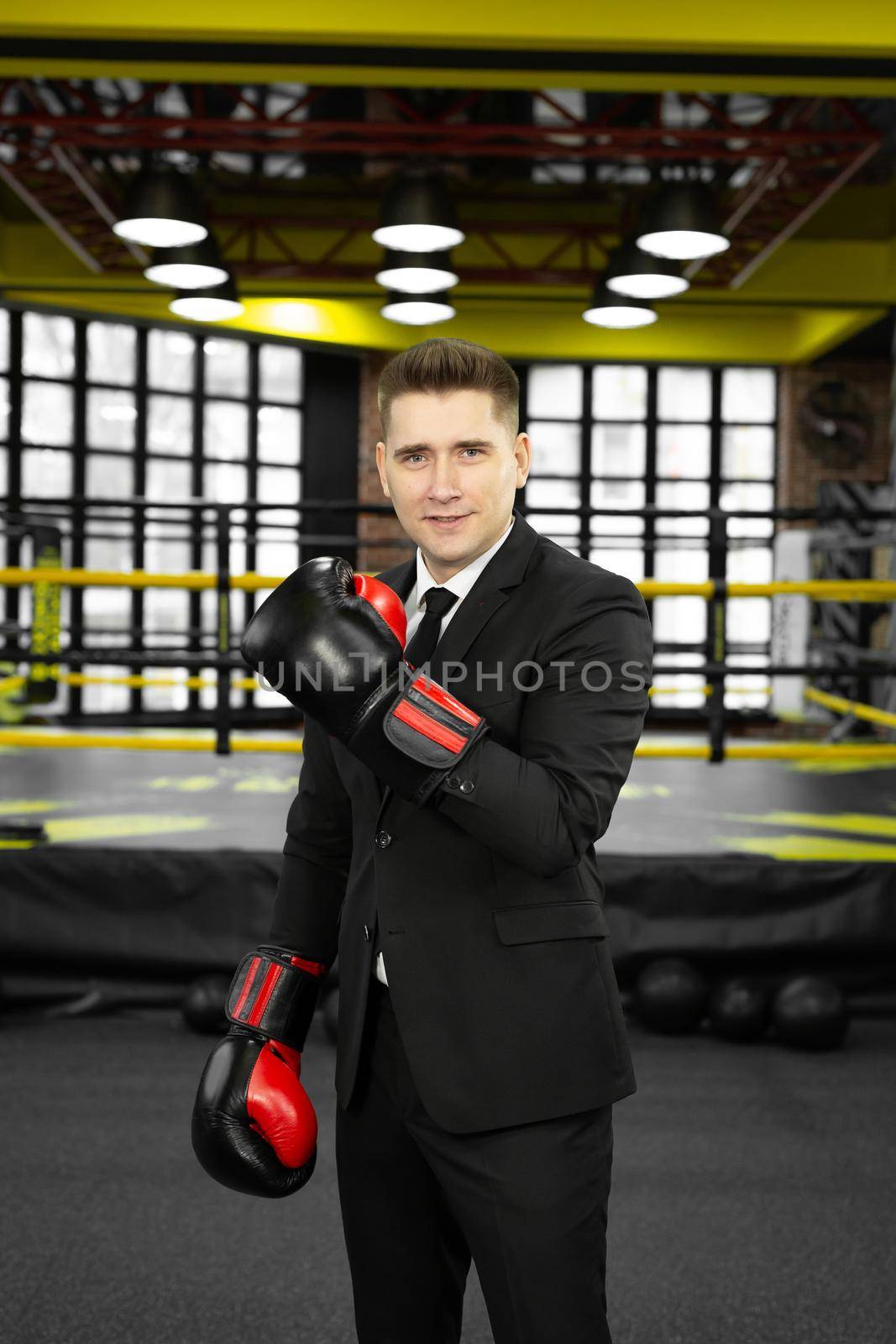 Portrait of a young male businessman in boxing gloves in the ring by StudioPeace