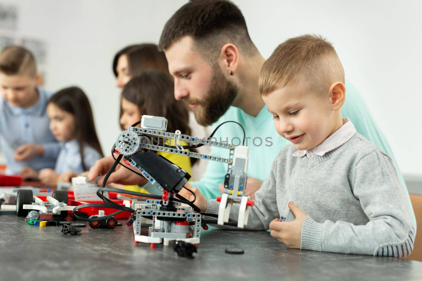 Young father and son assemble a construction kit at a robotics school by StudioPeace