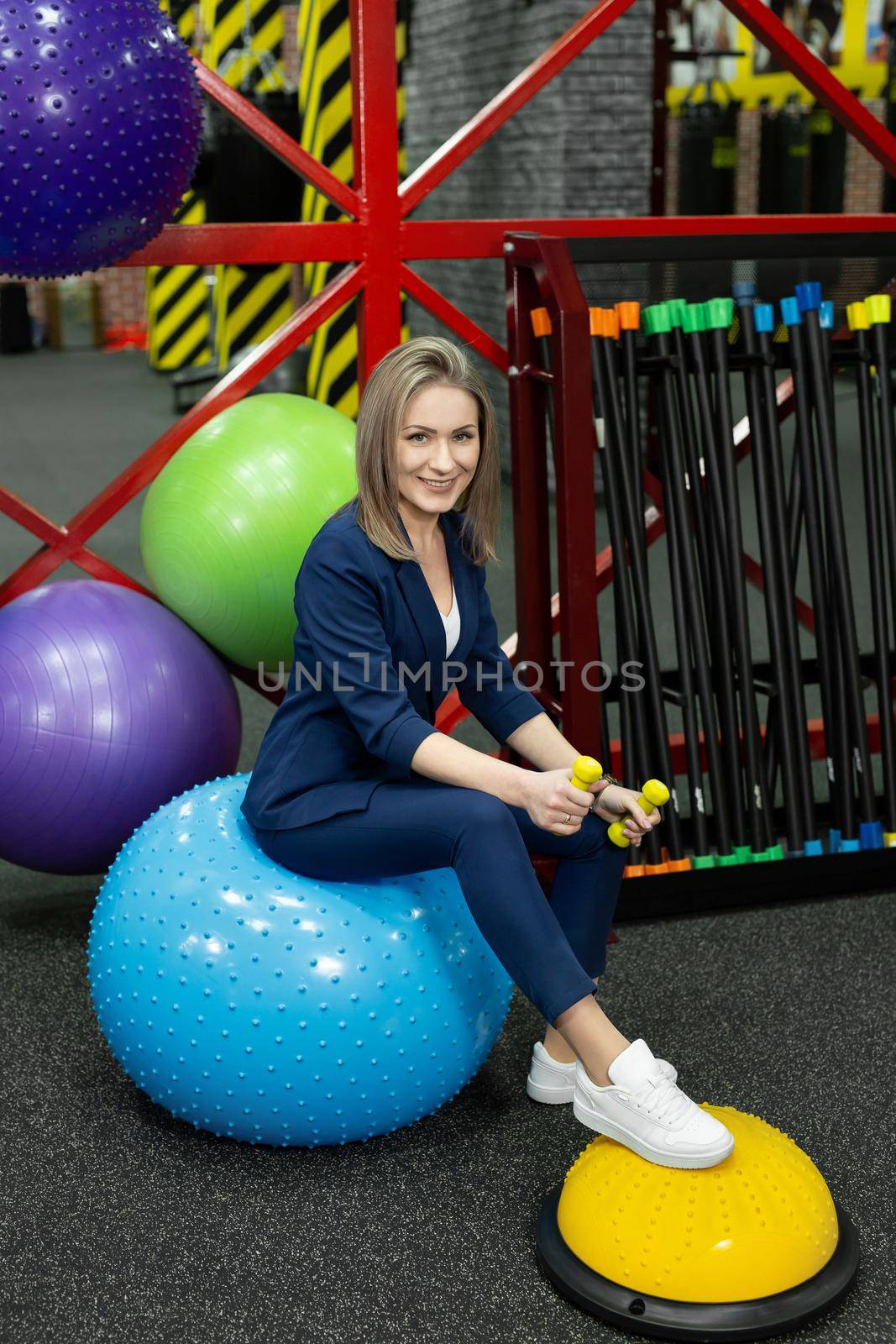 Young beautiful female businesswoman with dumbbells in the gym.