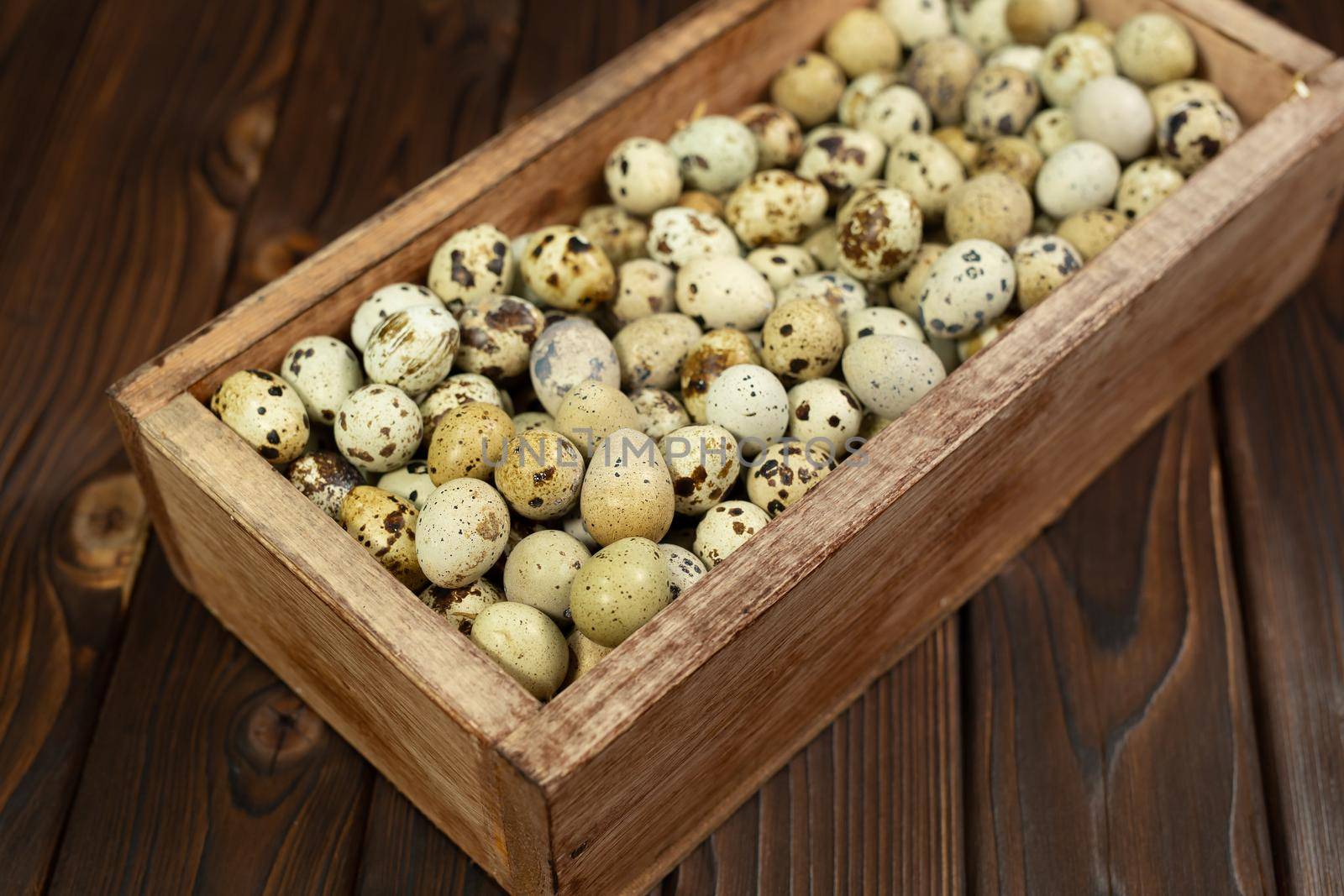 Lots of quail eggs in a wooden box on the background