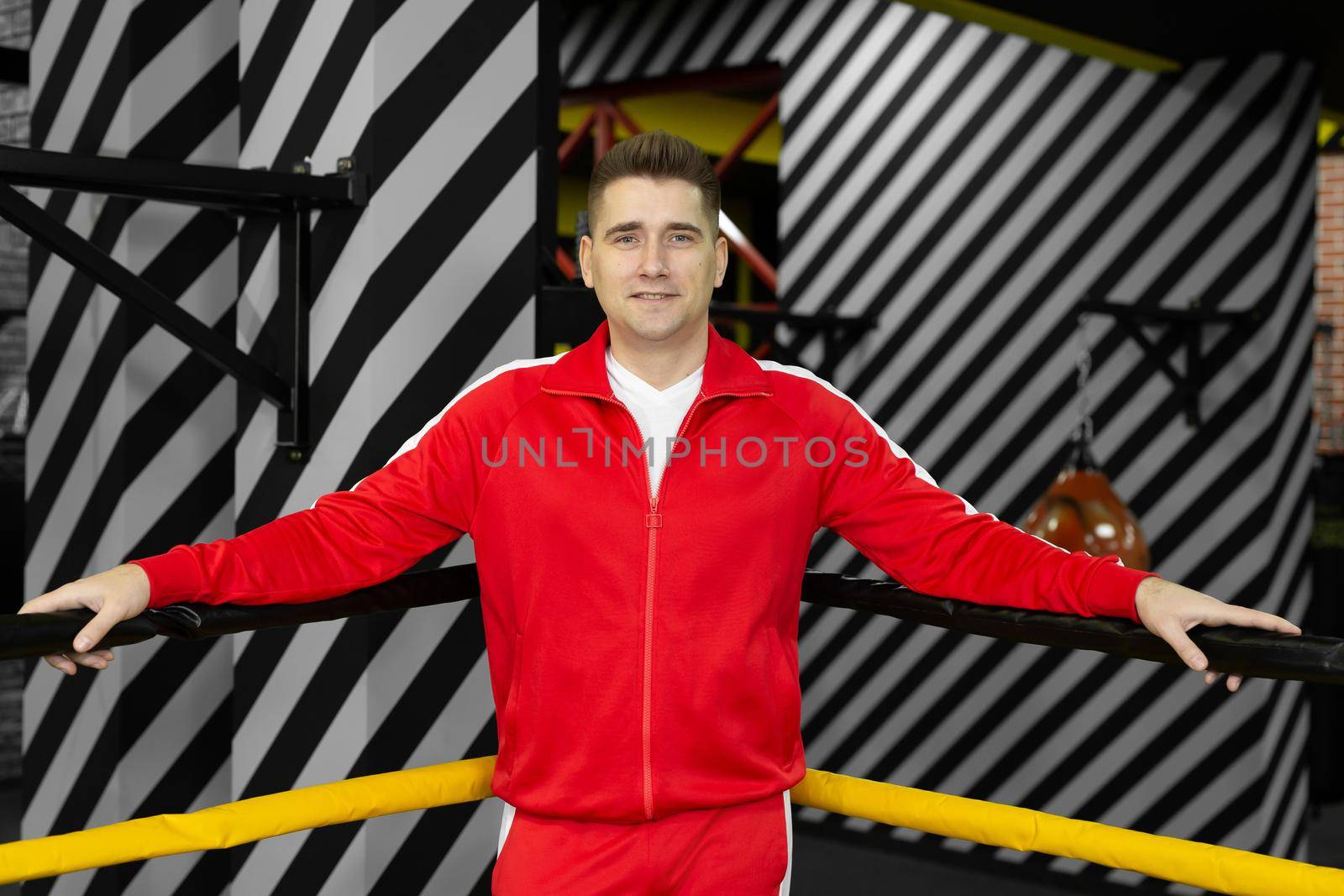 Man in a red tracksuit poses and has fun in the boxing ring