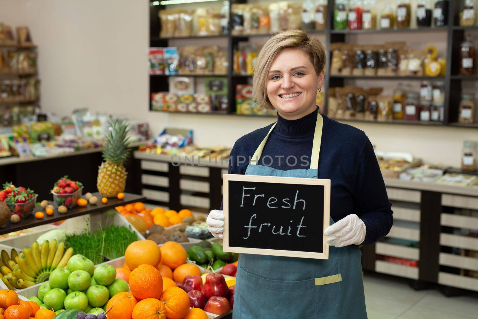Portrait of a young saleswoman with a sign in her hands fresh fruit.