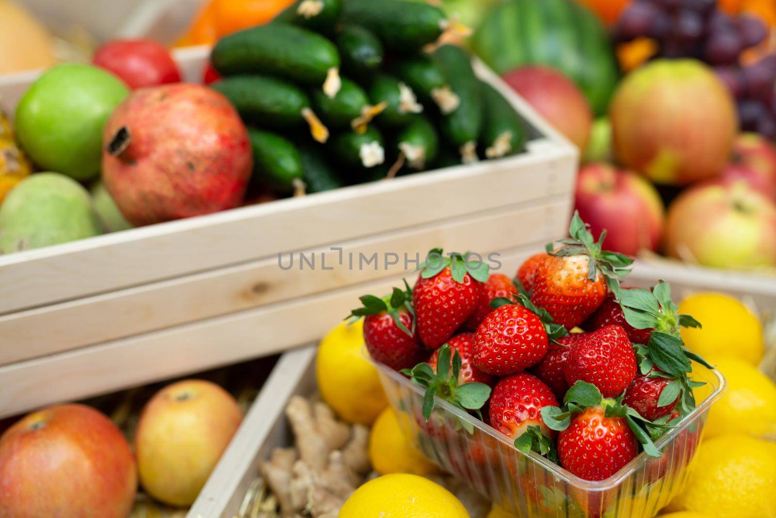 Tray of strawberries on the counter of a vegetable store among vegetables and fruits by StudioPeace