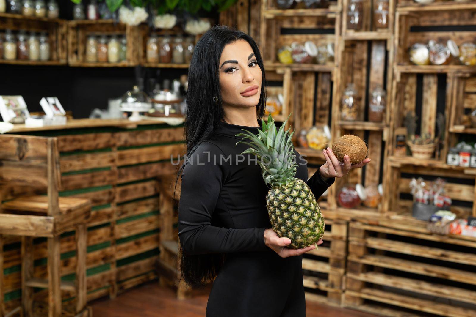 A young happy woman is holding and selling fresh fruit in a health food store.