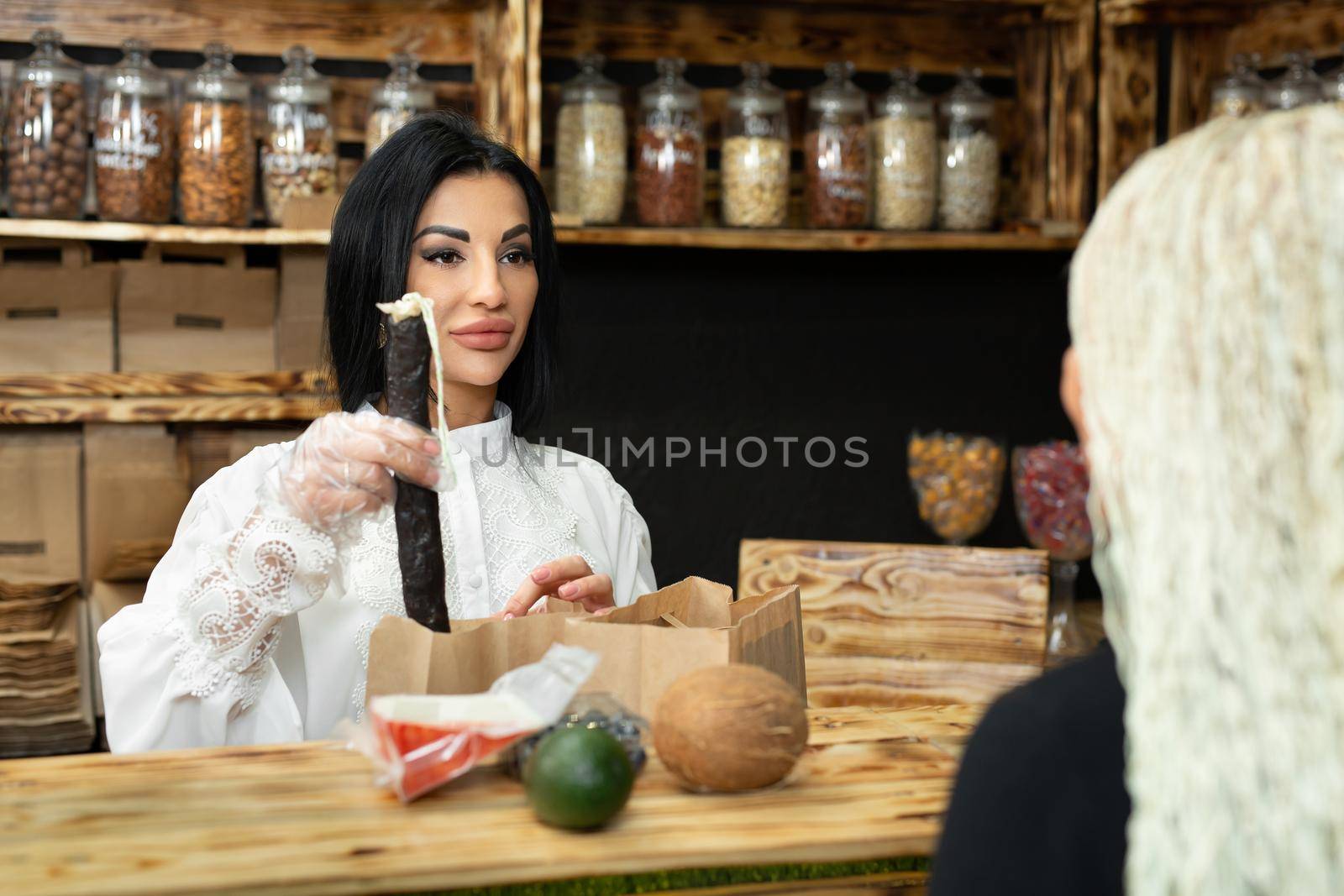Saleswoman packs a shopping bag with goods in a health food store.