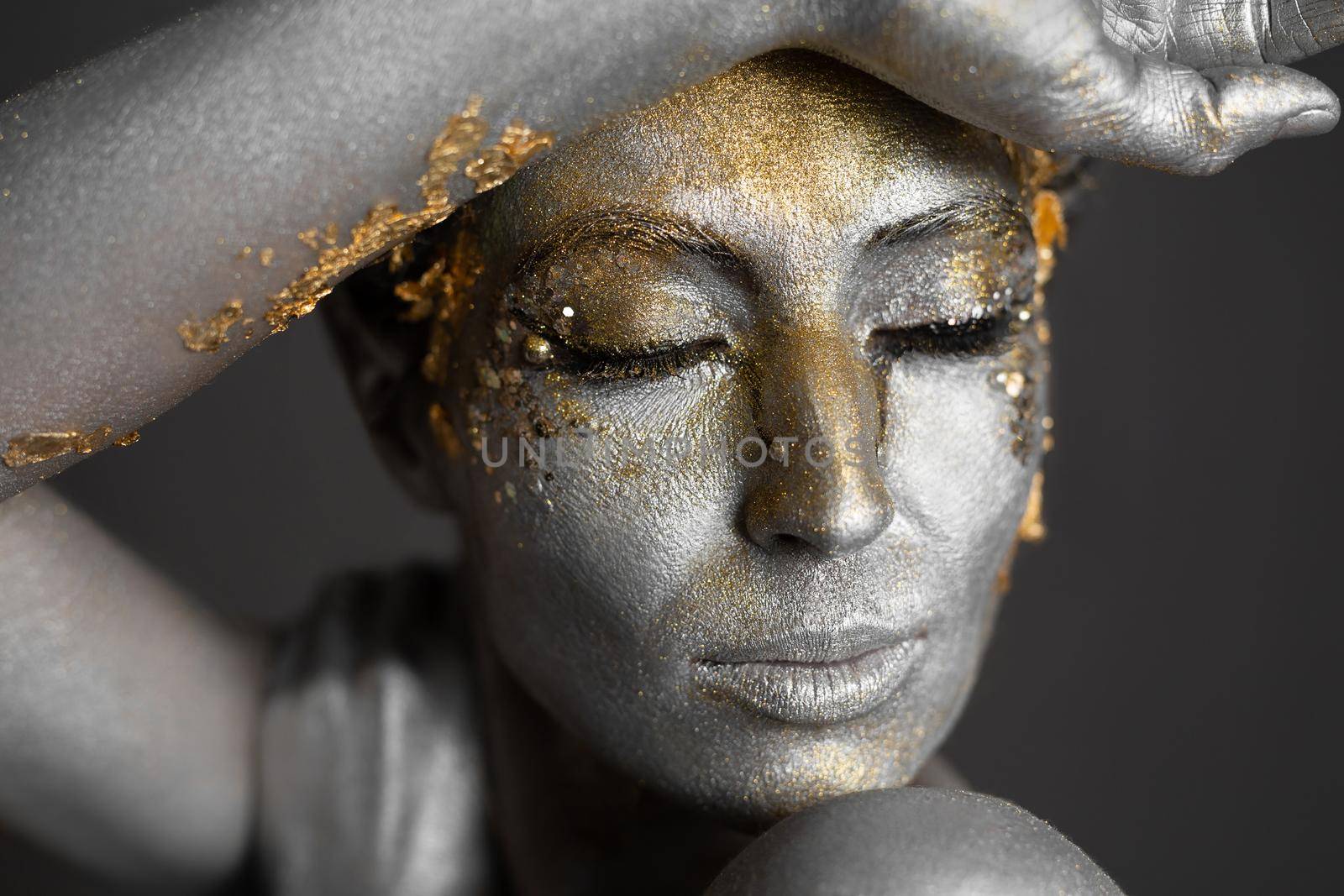 Portrait of a beautiful female model with gold and silver paint on her skin and hair in the studio by StudioPeace