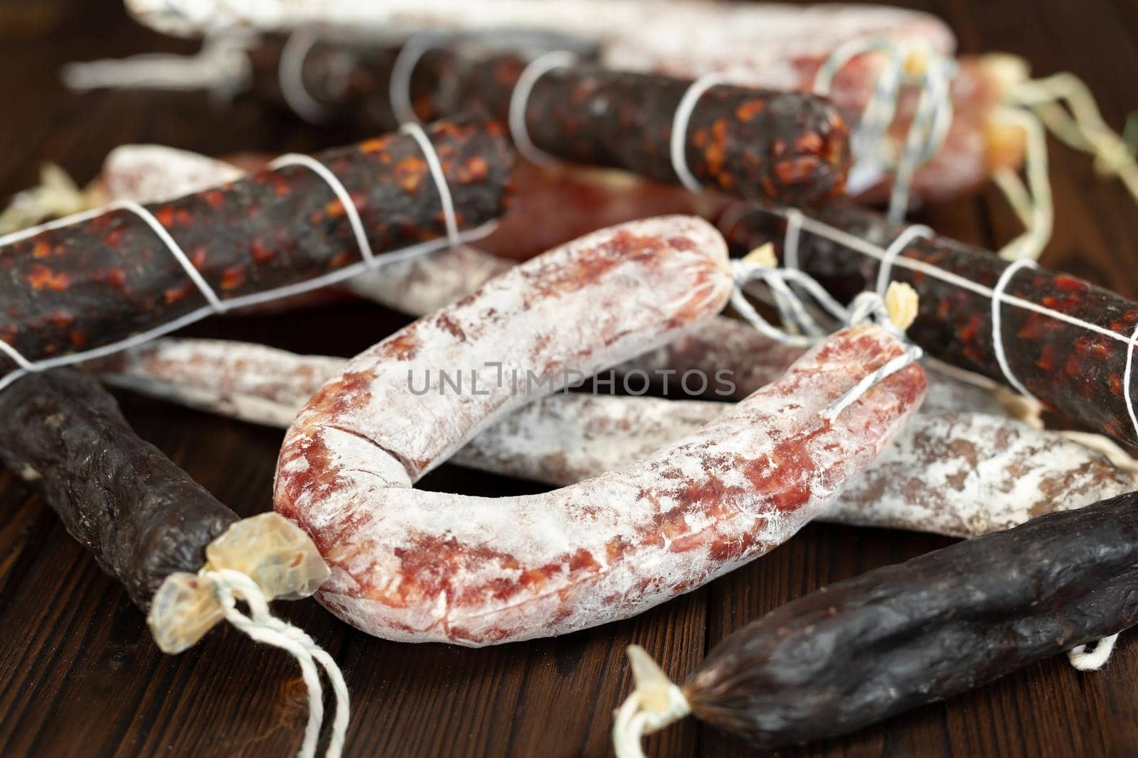 A variety of sausage products in close-up on a brown wooden background.