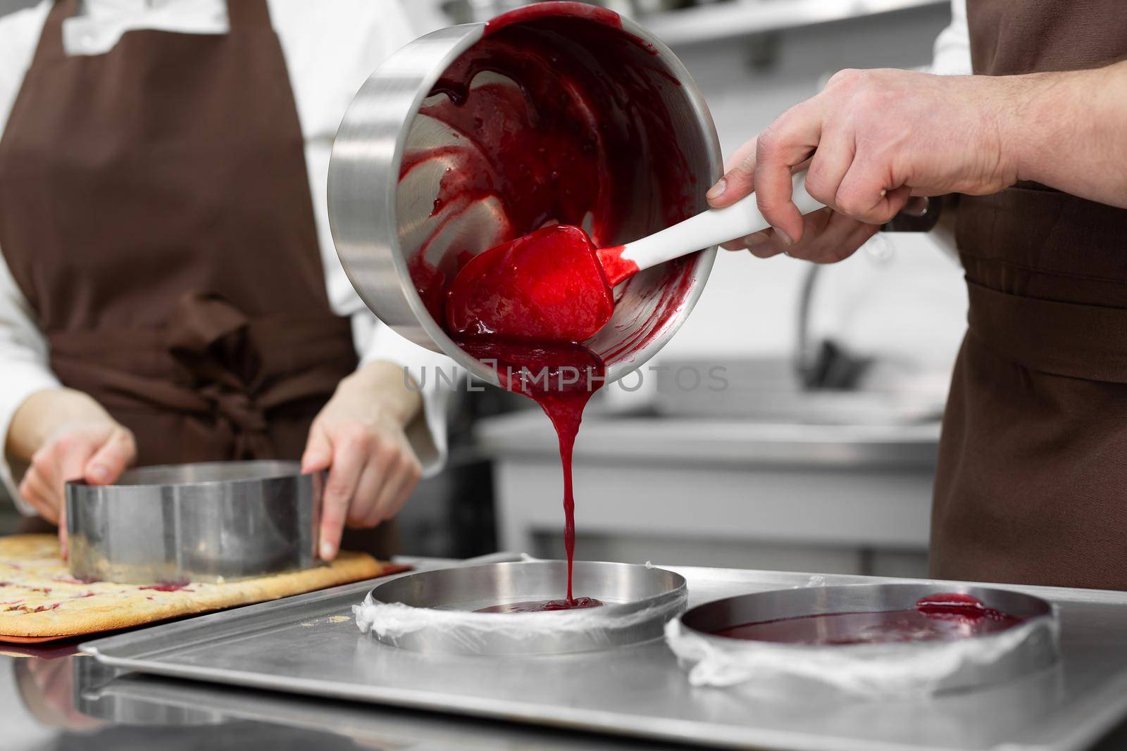 Woman and a man confectioners prepare berry filling for mousse cake.