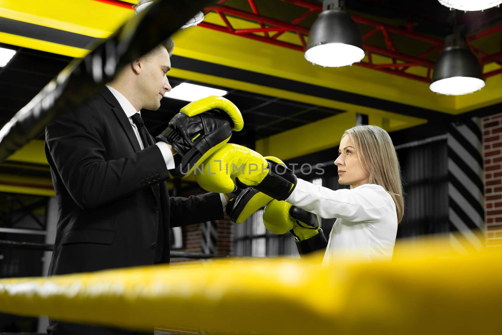 Boss trains his employee in boxing gloves in the ring