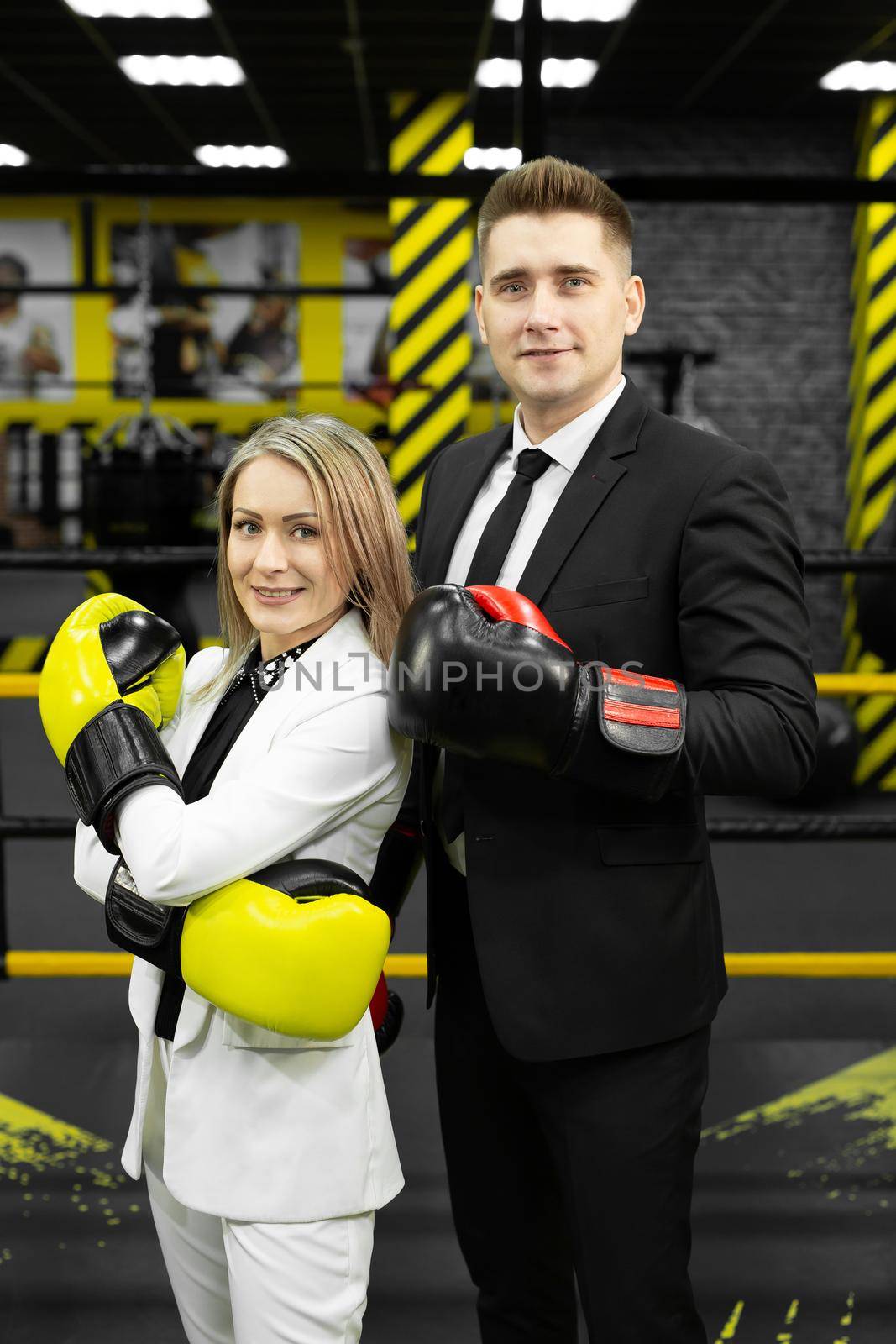 Colleagues, a man and a woman in business suits and boxing gloves in the ring.
