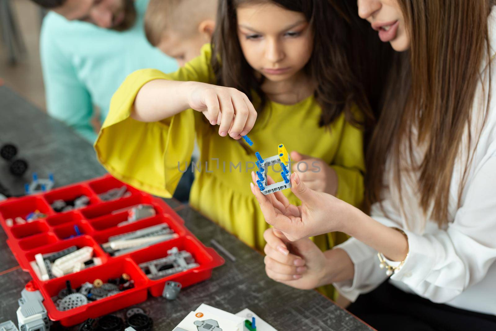 Close-up of a mother and daughter's hands at school making a robot controlled from a construction kit.