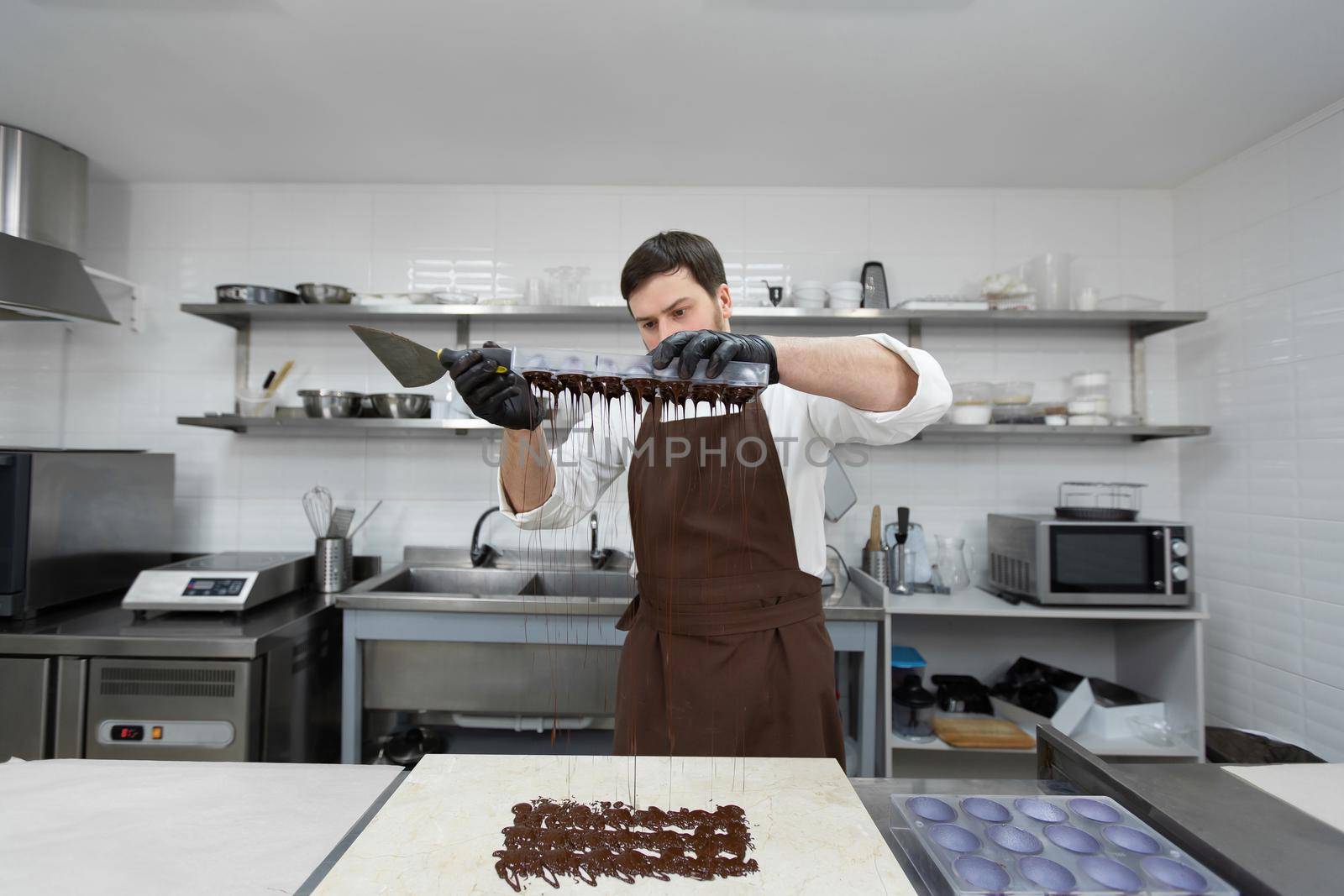 Chef or chocolatier makes sweet chocolates in a professional kitchen