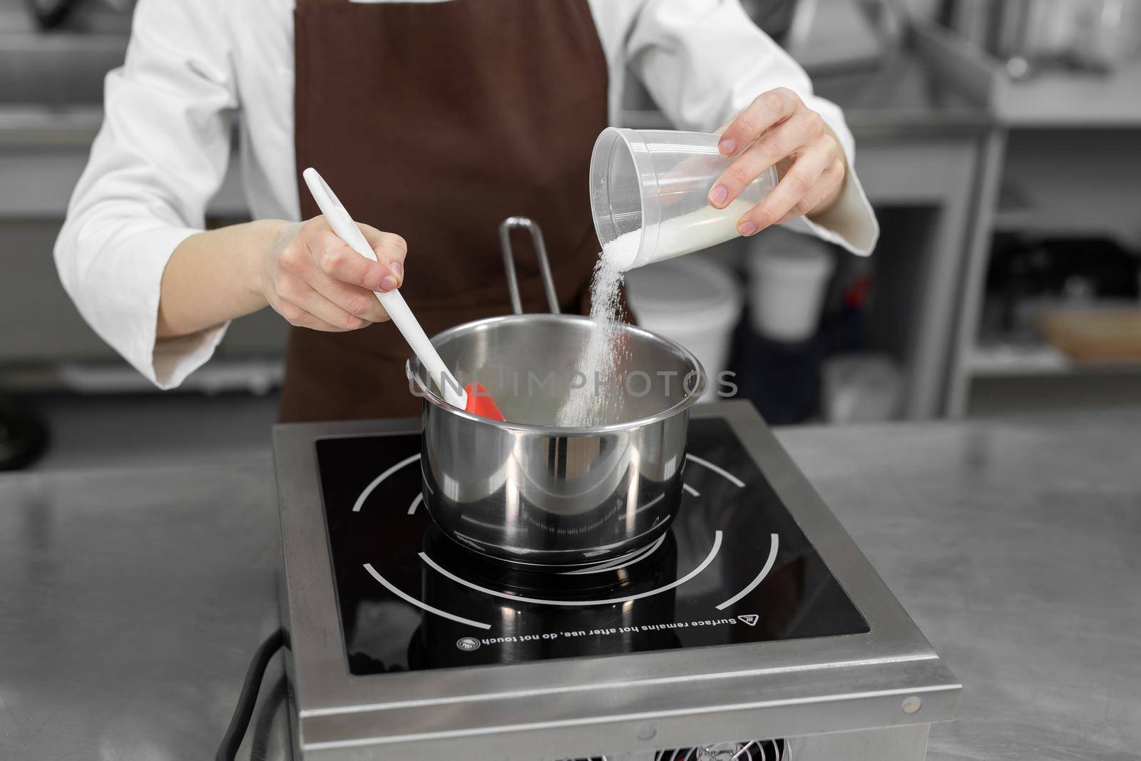 Pastry chef pours the sugar into a saucepan