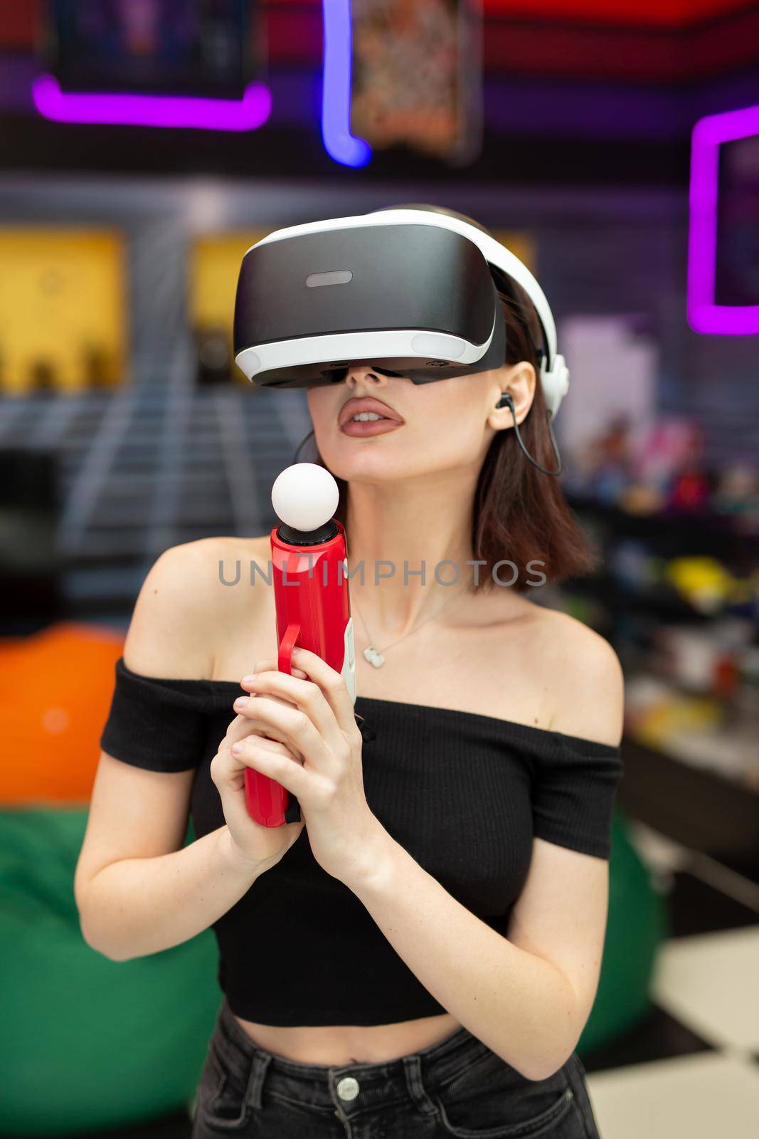 Young woman plays on a video games console, an emotional gamer shoots a game using a gun controller in a game club. VR