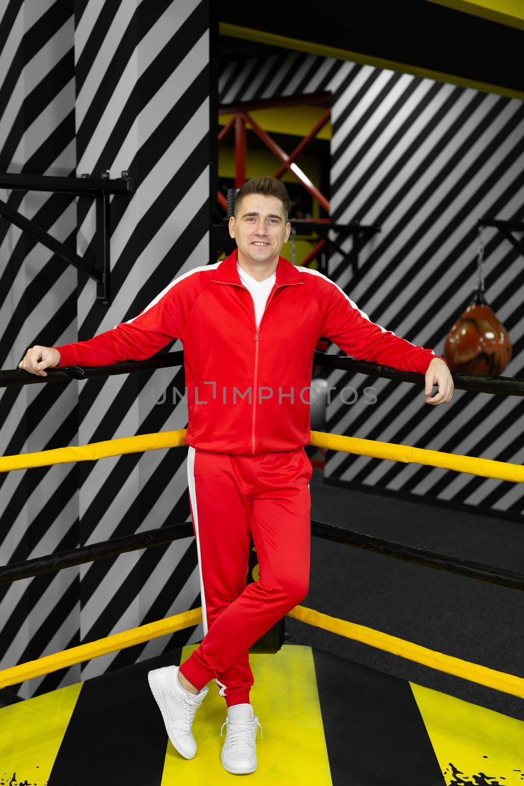 Man in a red tracksuit poses and has fun in the boxing ring