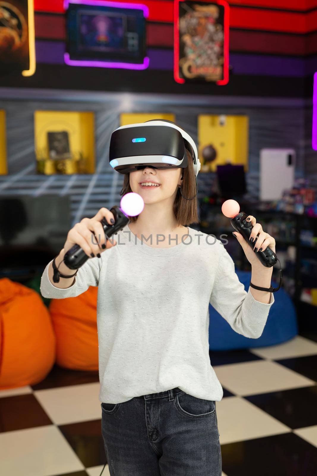 Child, a teenage girl playing on a game console in virtual reality glasses shooting a game with a remote control gun in a game club. VR. by StudioPeace