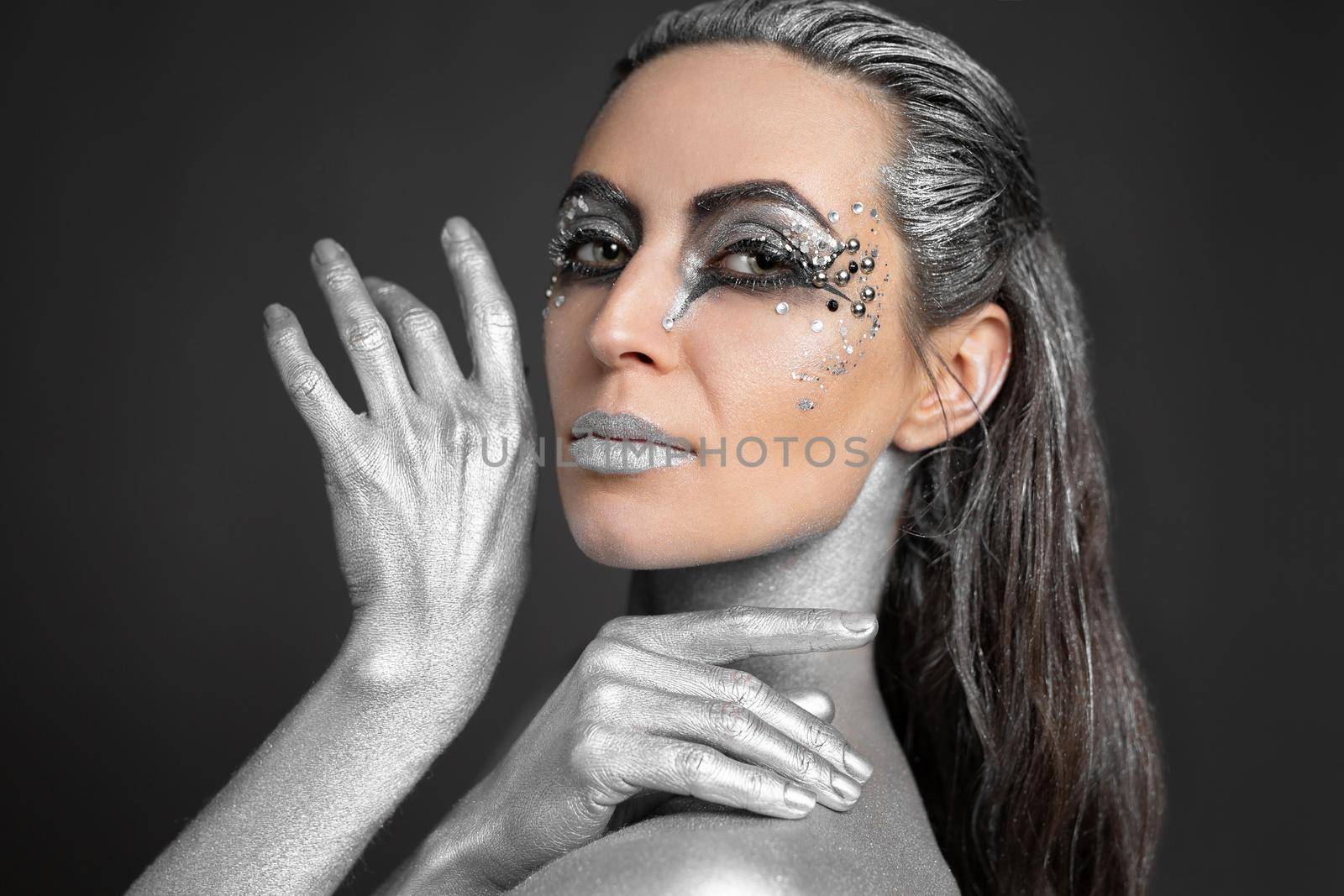 Portrait of a beautiful woman with silver paint on her skin and hair.