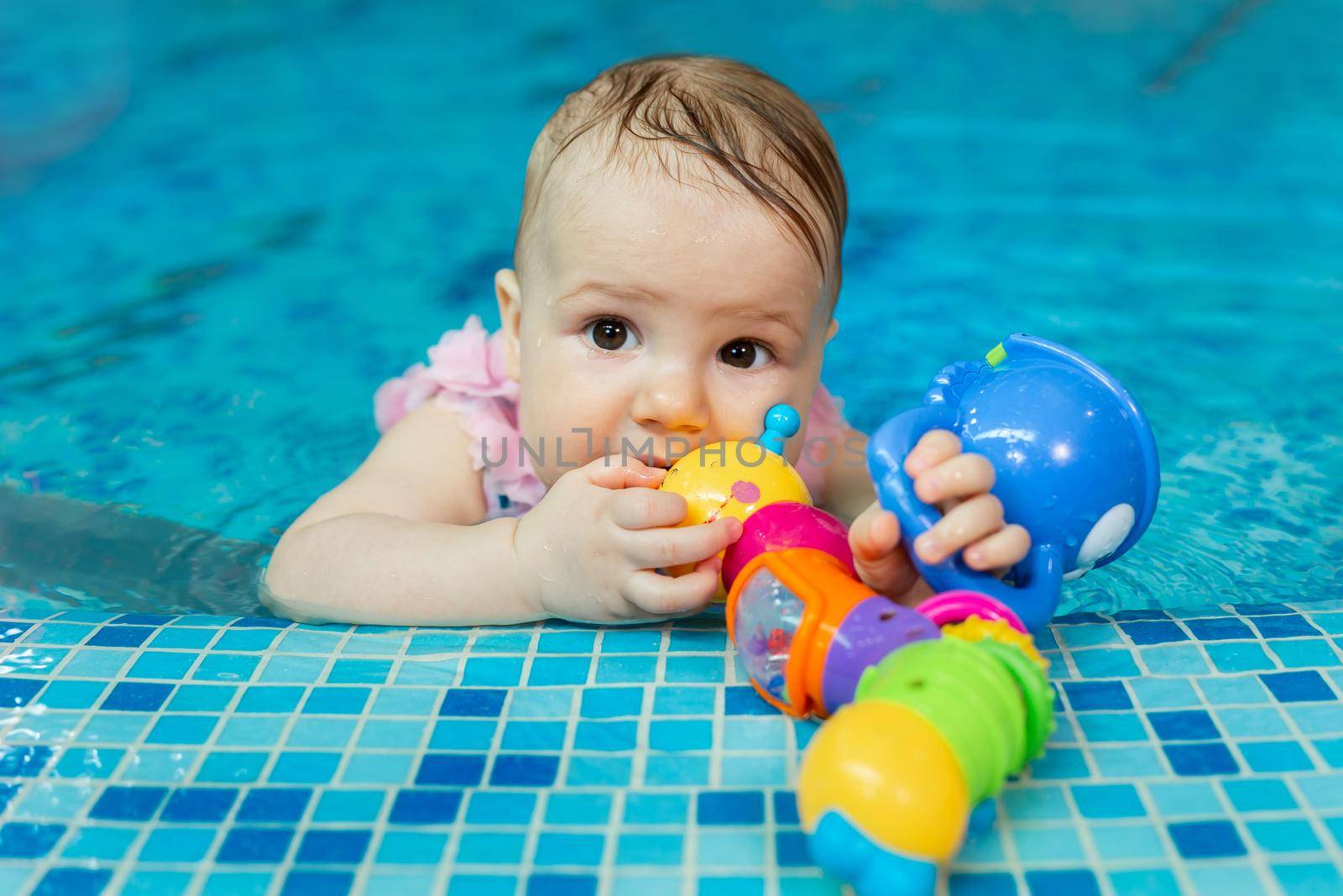 Little baby girl is playing with bright toys in the pool by StudioPeace