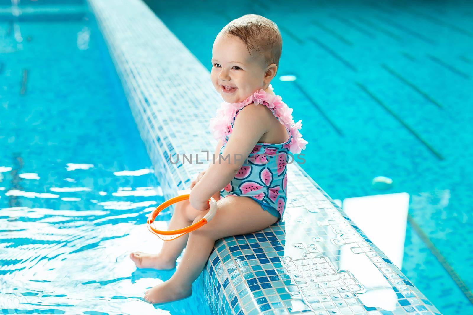 Little girl is laughing in the pool at a swimming lesson.