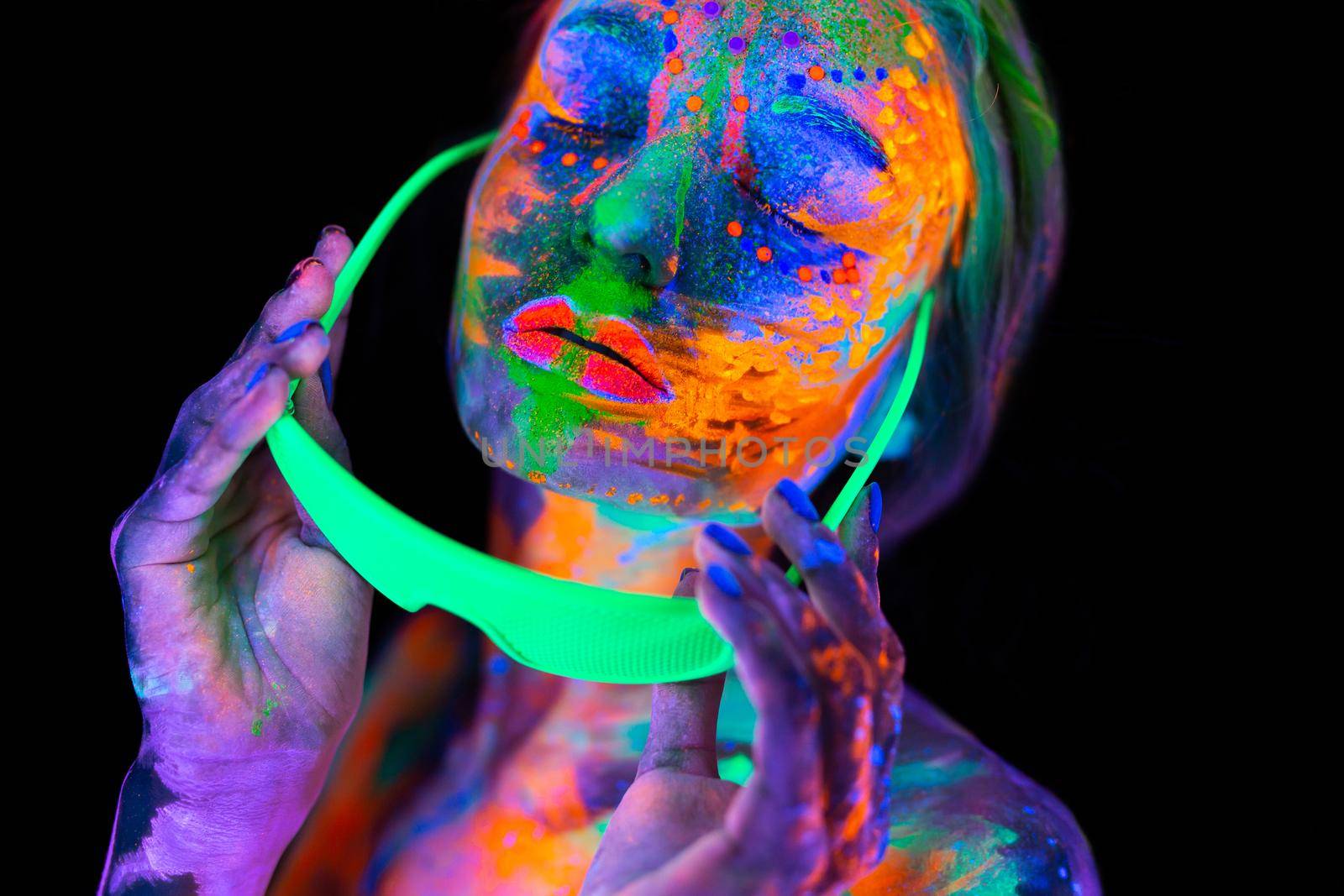 Beautiful model woman wearing glasses with colorful bright fluorescent makeup in neon light, nightclub disco.