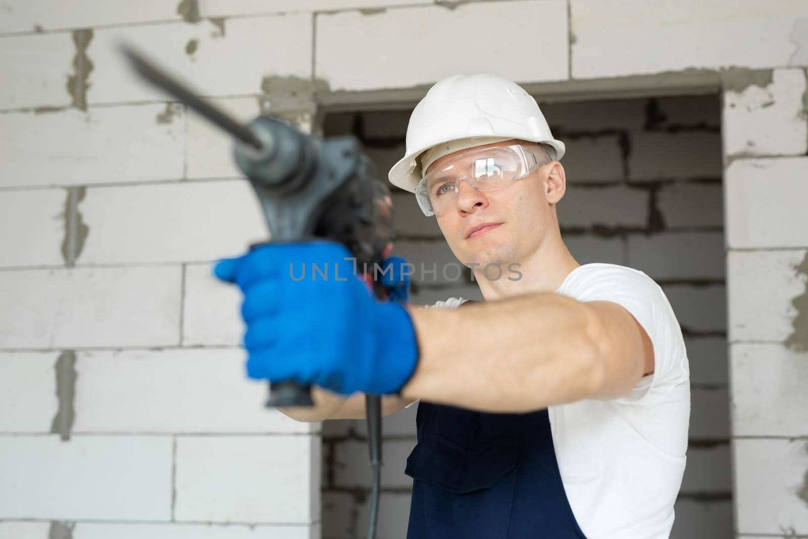 Close-up of a drill in the hands of a professional builder.