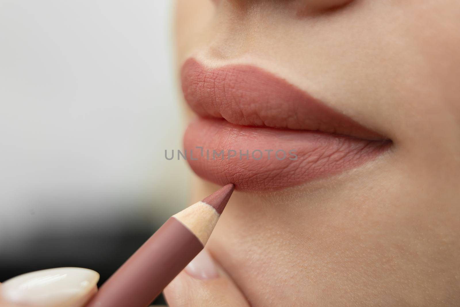 Lip makeup. Close-up of a cosmetologist painting her lips with a pencil before permanent makeup. by StudioPeace