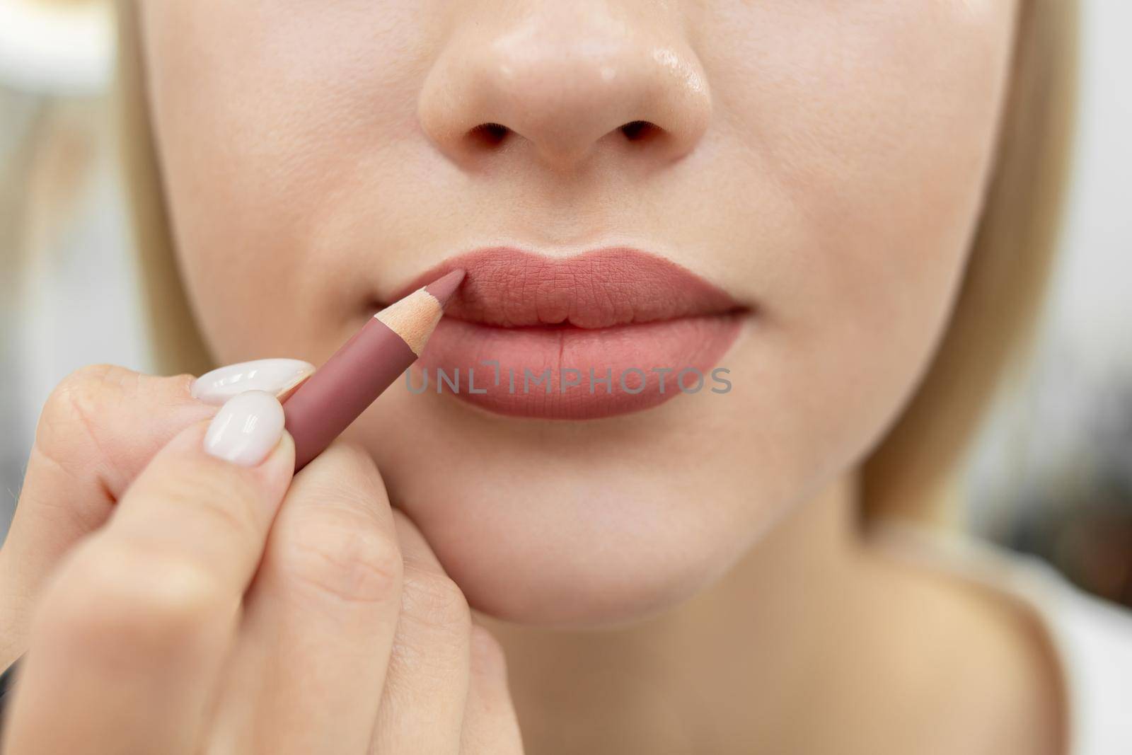 Lip makeup. Close-up of a cosmetologist painting her lips with a pencil after permanent makeup by StudioPeace