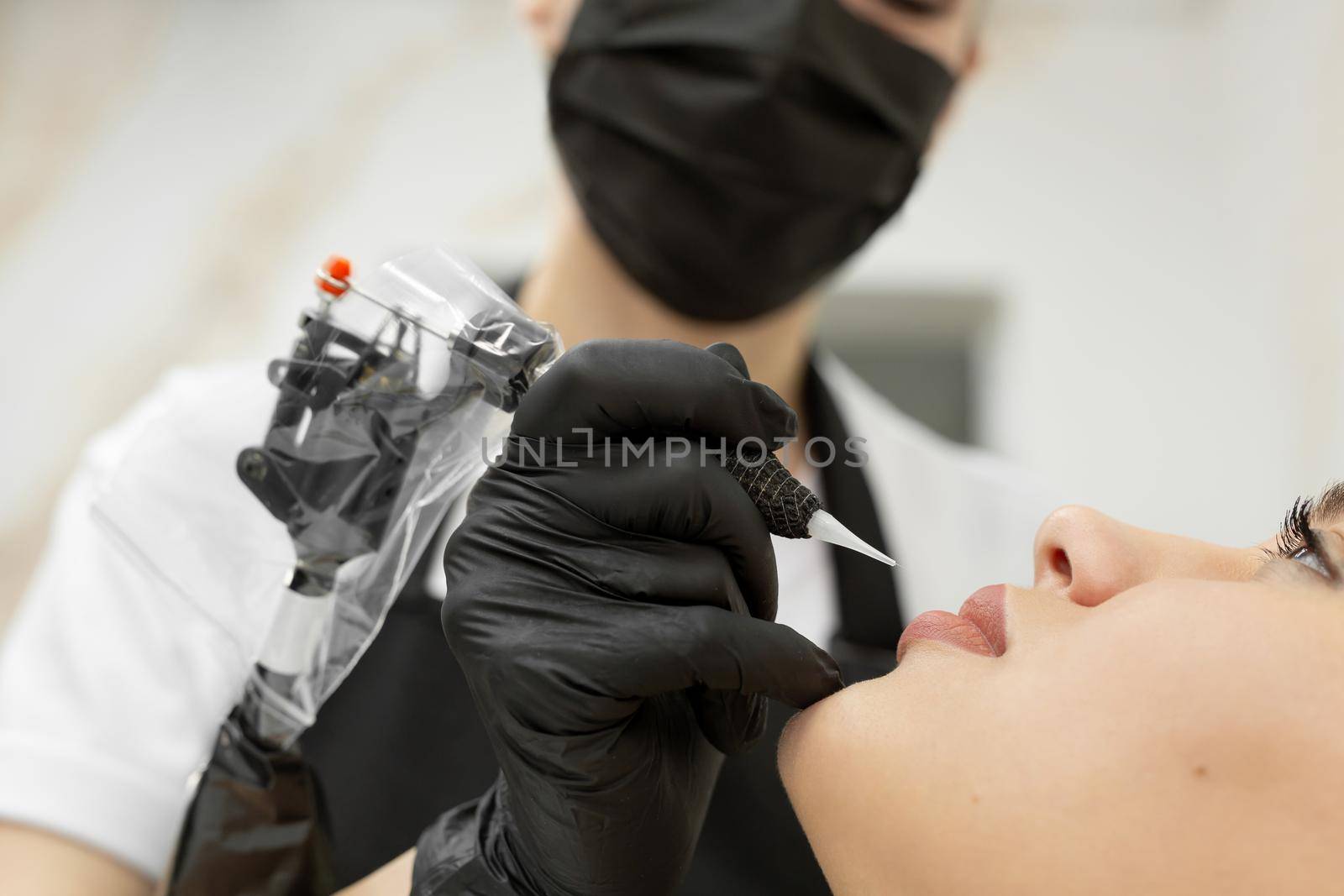 Cosmetologist applies permanent makeup to the lips in the salon.