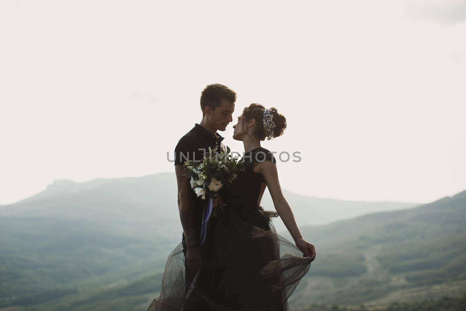 Woman and man in black clothes outdoors. Black wedding dress.