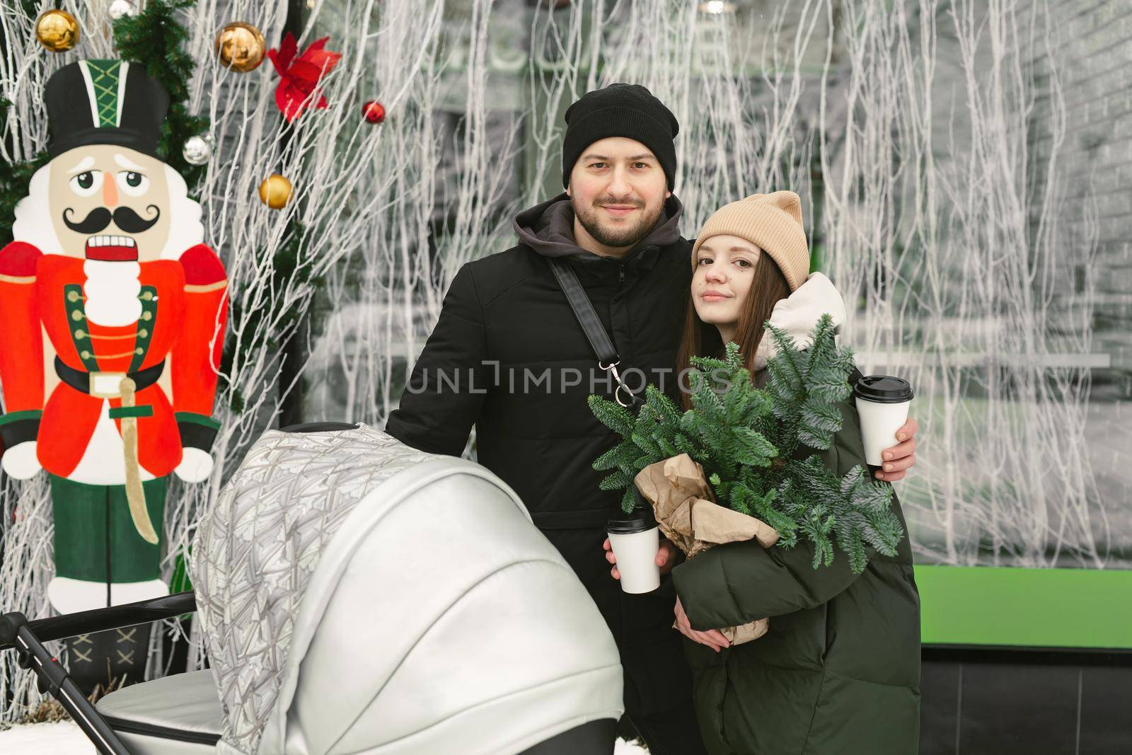 Portrait of a young family, a man and a woman with a stroller on a walk on a winter day by StudioPeace