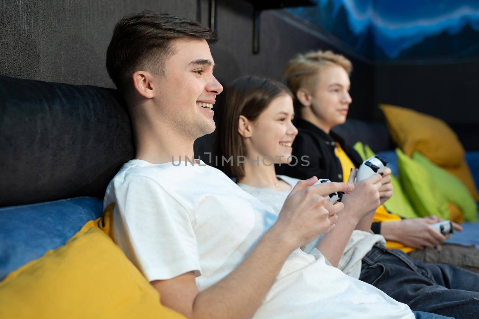 Group of friends of teenagers, boys and girls playing video games on a console in a game club by StudioPeace