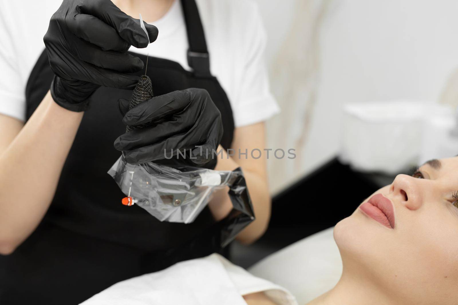 Cosmetologist applies permanent makeup to the lips in the salon.