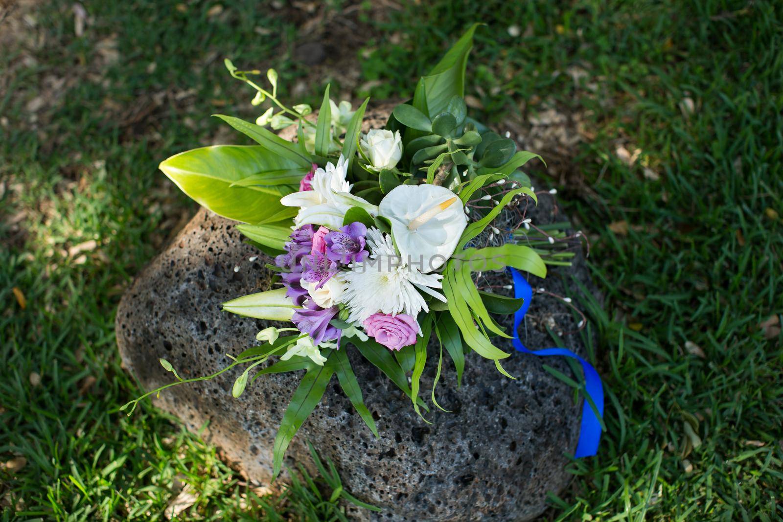 A beautiful wedding bouquet on a stone in the park.