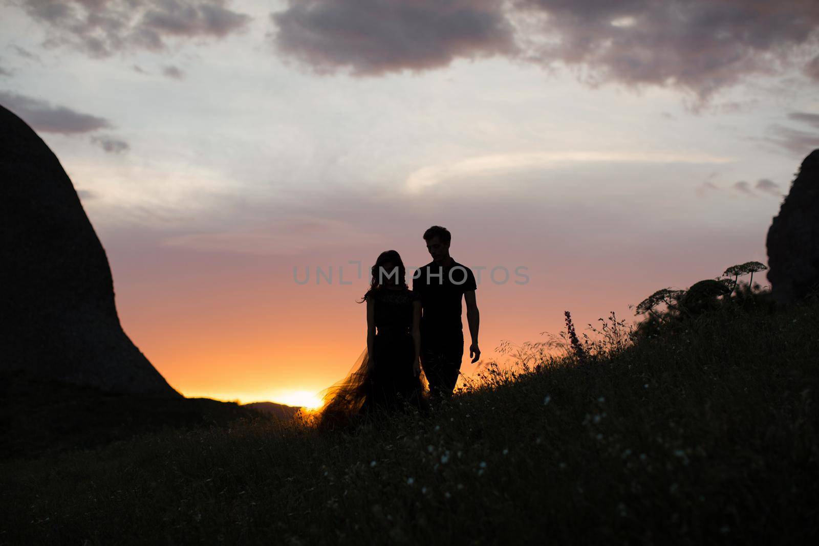 Silhouettes of a young couple lovers at sunset in rays of setting sun by StudioPeace