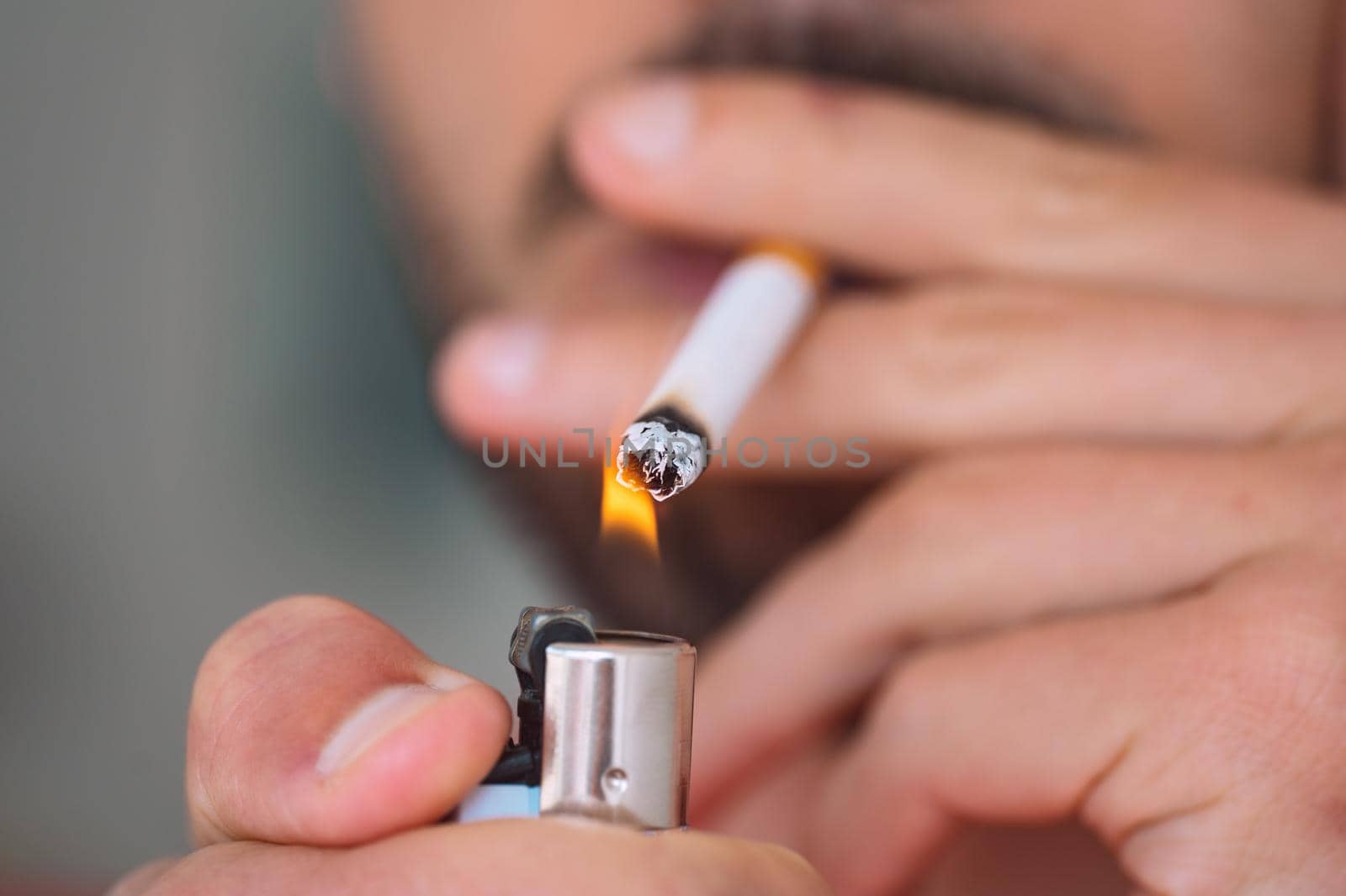 Closeup of young man lighting and smoking cigarette. Smoking addiction and bad habit concept. High quality photo