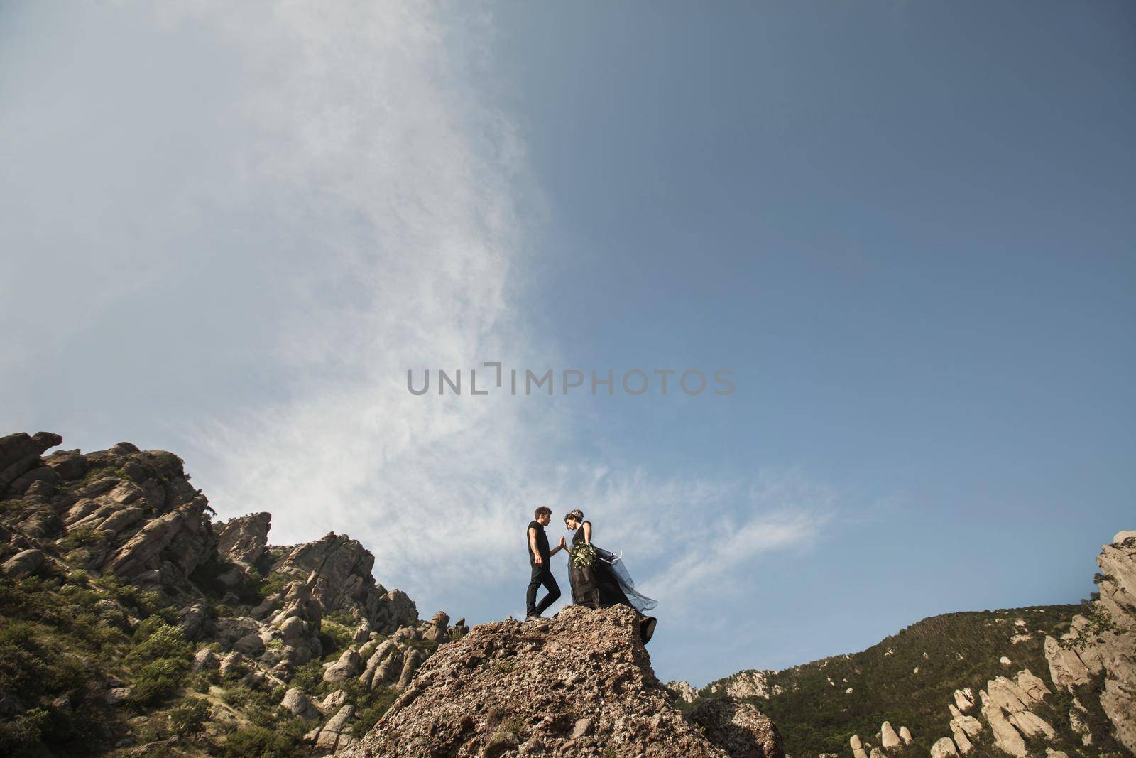 Woman and man in black clothes outdoors. Black wedding dress.