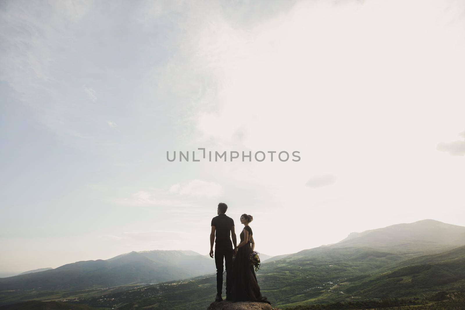Woman and man in black clothes outdoors. Black wedding dress.