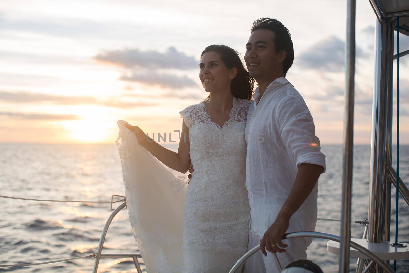 The bride and groom on a catamaran. The sunset in the open Indian ocean.