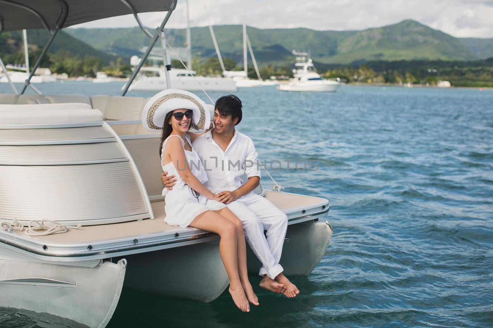 Young couple is sailing on a yacht in the Indian ocean. Man and woman sit on the edge of the yacht