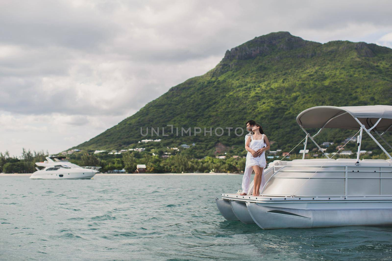 Young couple is traveling on a yacht in the Indian ocean. On the bow of the boat, a loving family embraces