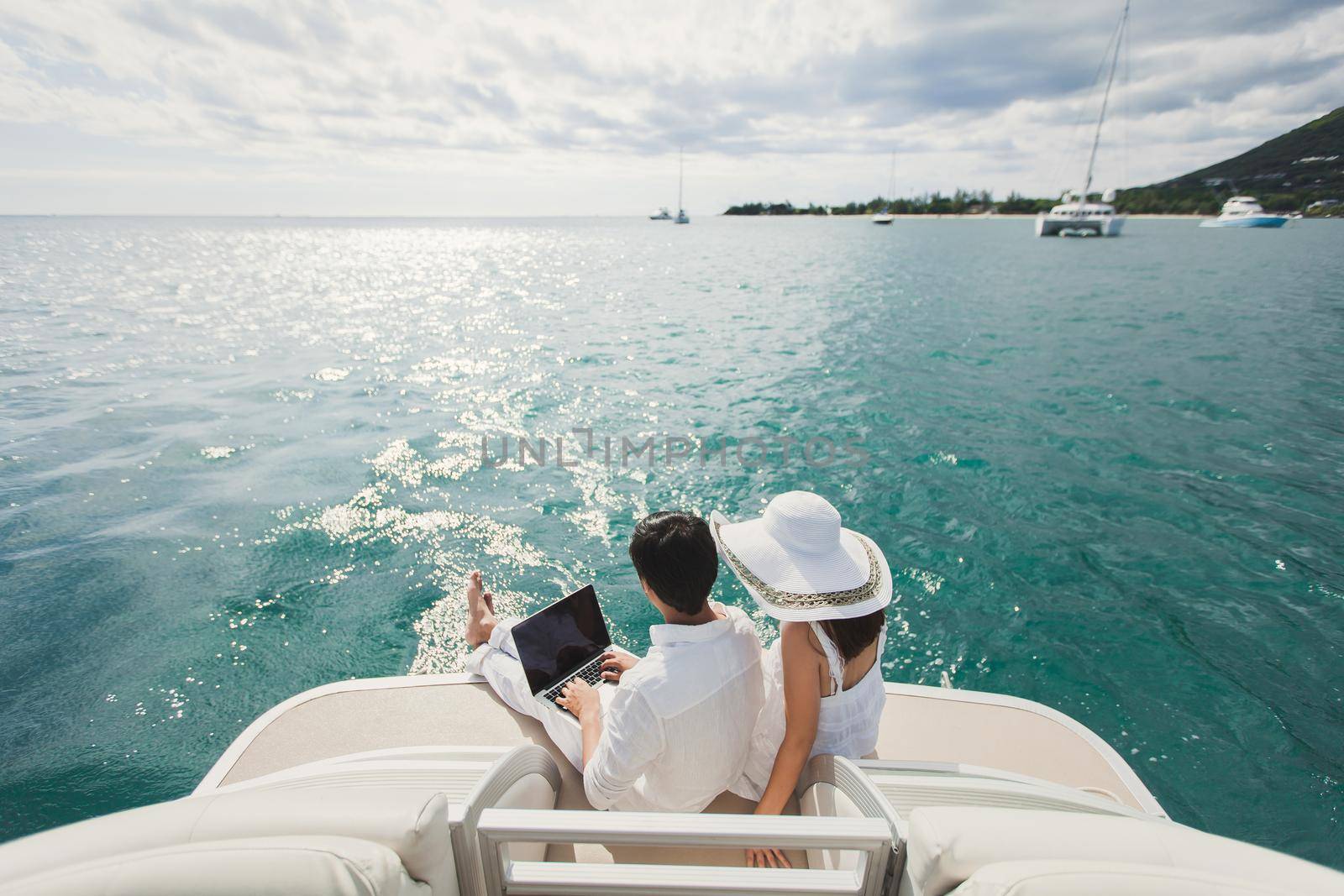 Two business people working with laptop on a sailing boat - sailing trip by StudioPeace