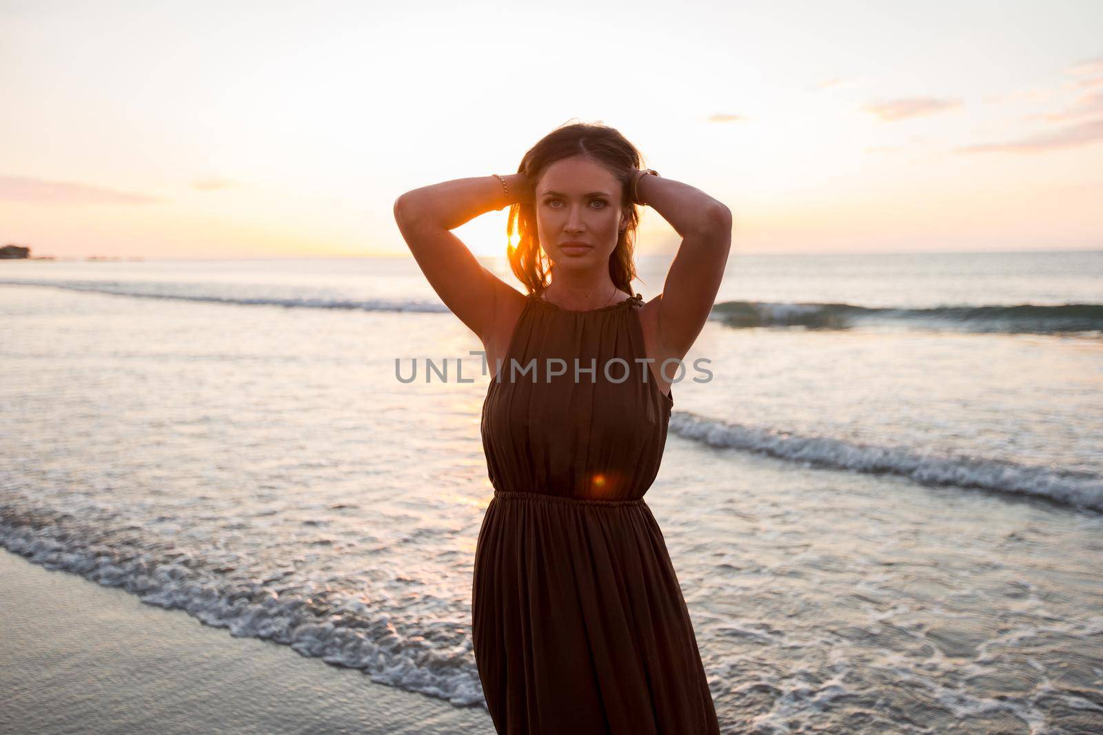 Beautiful woman on sunset background. Colorful dawn over the sea. Carefree woman enjoying the sunset on the beach. Happy lifestyle