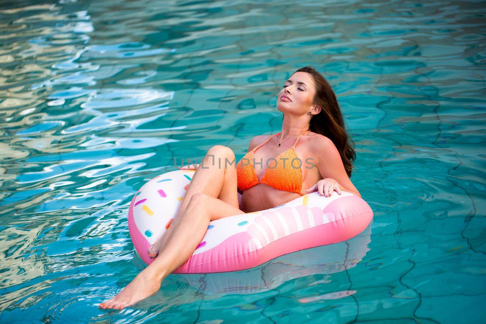 Young girl in sprinkled doughnut float at pool