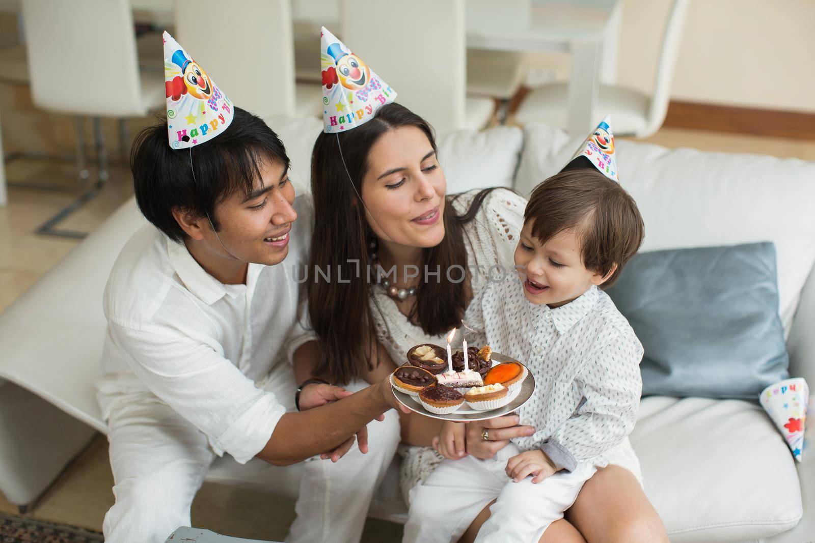 Happy family blowing candles together for a birthday at home
